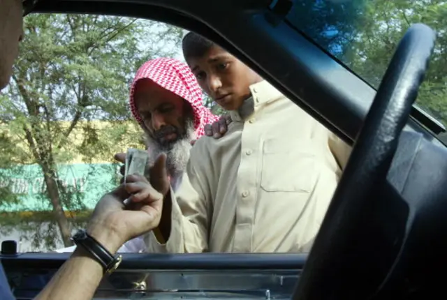 A driver hands money to beggars in Riyadh