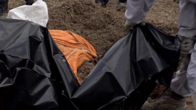 Бучадаги оммавий қабрдан топилган жасадни қопга солиш