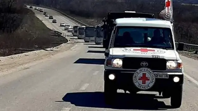 Red Cross car leading the convoy of refugee vehicles