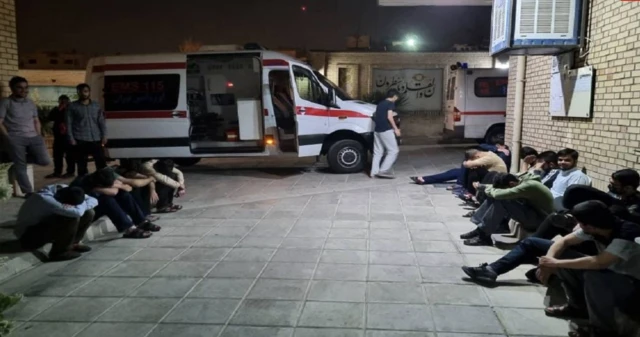 دانشجویان در بیرون دانشگاه منتظر آمبولانسی که در تصویر دیده می‌شود