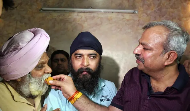 दिल्ली बीजेपी के नेता आदेश गुप्ता तेजिंदर पाल सिंह बग्गा के पिता को मिठाई खिलाते हुए