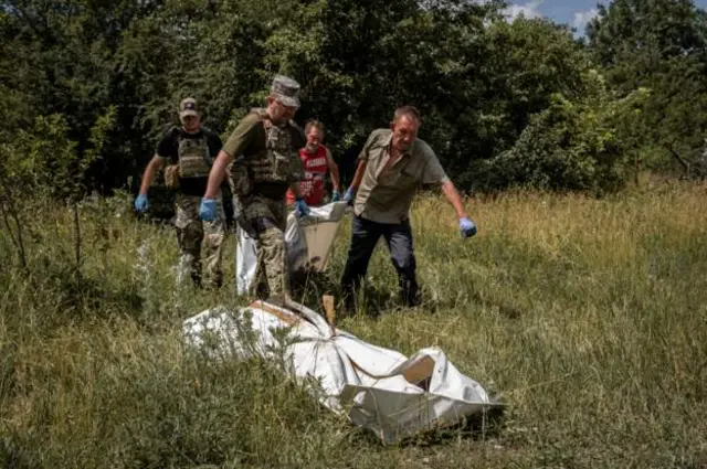 Солдати J9 і копачі могил, зокрема Юрій (попереду справа), виносять тіла