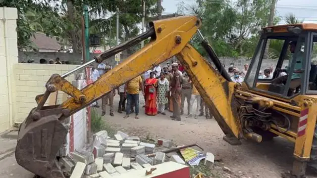 శివాలయం గోడను కూల్చుతున్న బుల్డోజర్