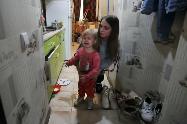 Женщина и ребенок в доме в Харькове, частично разрушенном после попадания российской ракеты, 12 августа 2022 года