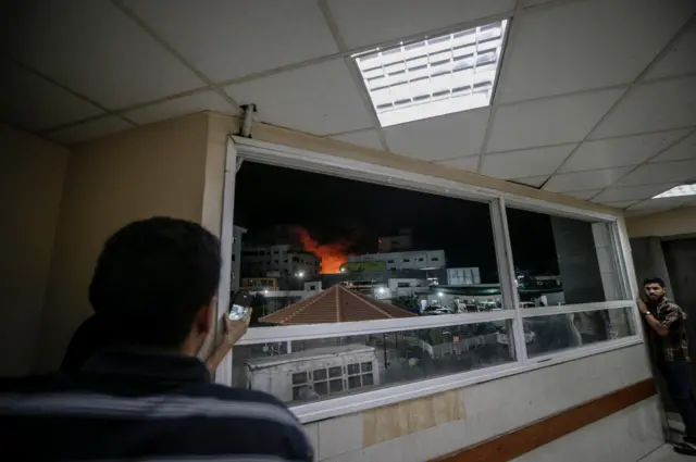 فلسطينيون يشاهدون الدخان يتصاعد خلف بنايتهم بعد غارة جوية إسرائيلية على مدينة غزة