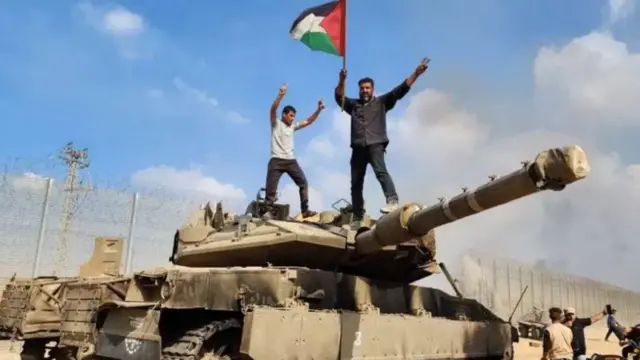 فلسطينيون يحتفلون بالاستيلاء على دبابة إسرائيلية بعد ضربها من مقاتلي حماس