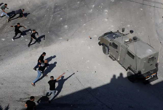 فلسطينيون يلقون حجارة على مركبة عسكرية إسرائيلية