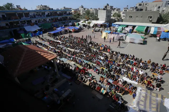 فلسطينيون يؤدون صلاة الجمعة في حديقة المدرسة التابعة لوكالة الأمم المتحدة لإغاثة وتشغيل اللاجئين الفلسطينيين (الأونروا) في دير البلح، وسط قطاع غزة