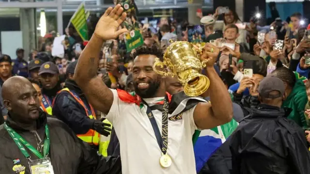 Nahodha Siya Kolisi akiwasalimia wafuasi wake wakati akishikilia Kombe la Webb Ellis Cup wakati timu ya raga ya Afrika Kusini ikiwasili.