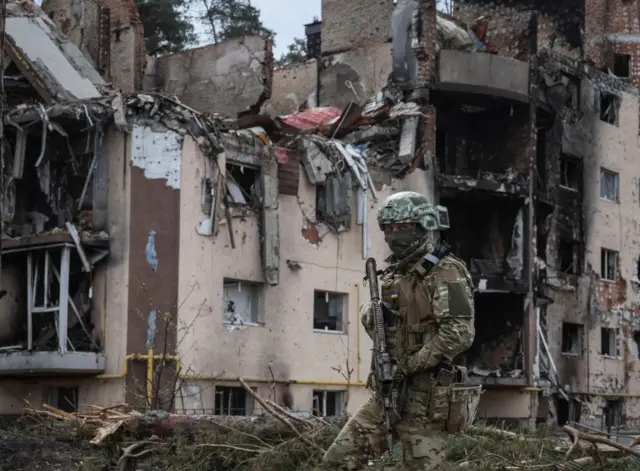 Украинский военный возле разрушенных российским обстрелом зданий в городе Ирпень в Киевской области