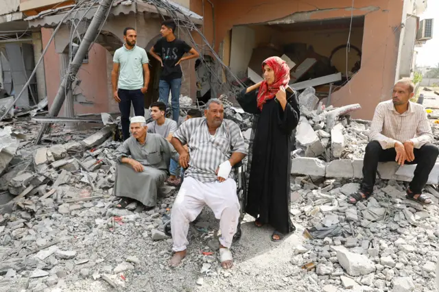 فلسطينيون يشاهدون فريق الدفاع المدني أثناء بحثهم عن الضحايا المحاصرين تحت أنقاض منزل دمر