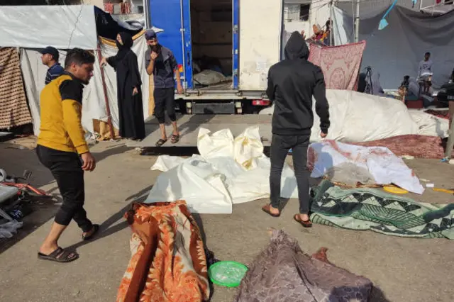 أشخاص يتفقدون جثث الضحايا الذين قتلوا في غارة إسرائيلية، وهي ملقاة على الأرض بالقرب من مجمع مستشفى الشفاء بمدينة غزة في 10 نوفمبر 2023.