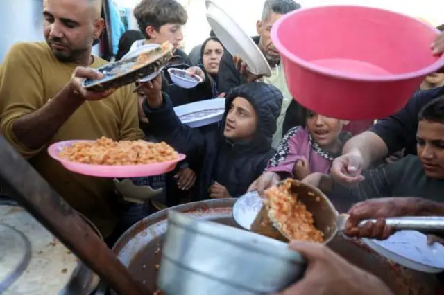 صورة التقطت يوم الخميس لفلسطينيين يصطفون للحصول على الطعام في حرم مستشفى الأقصى بوسط غزة، حيث يحتمون من القصف الإسرائيلي