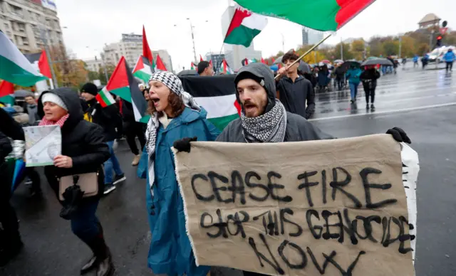 متظاهر يحمل لافتة تطالب بوقف إطلاق النار خلال مسيرة تضامن مع الفلسطينيين في غزة بالعاصمة الرومانية بوخارست
