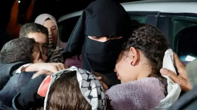 امرأة تحتضن مجموعة من الأطفال الصغار بعد إطلاق سراحها من الاعتقال في أحد السجون الإسرائيلية