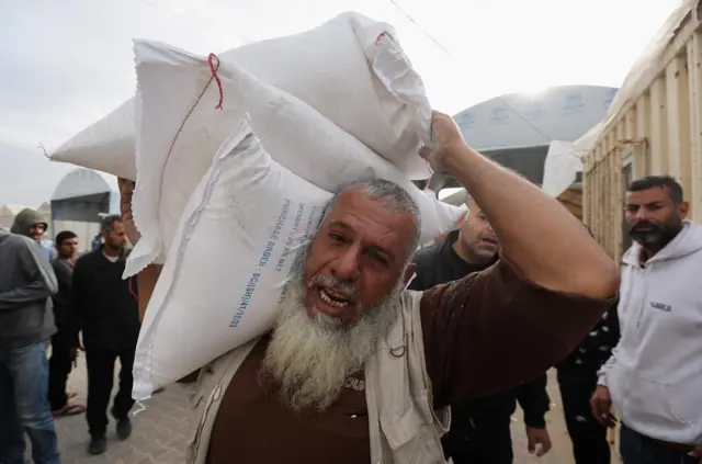 رجل فلسطيني يحمل أكياس الطحين التي وزعتها وكالة الأمم المتحدة لإغاثة وتشغيل اللاجئين (الأونروا) خلال هدنة مؤقتة بين حماس وإسرائيل