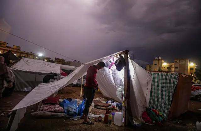 الفلسطينيون الذين نزحوا من شمال قطاع غزة يعدون خيامهم المؤقتة خلال ليلة ممطرة في بلدة خان يونس، جنوب قطاع غزة