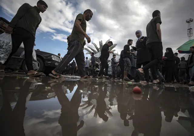 فلسطينيون يسيرون بجوار بركة مياه في خان يونس