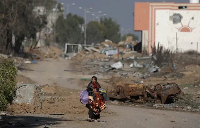 إمرأة من غزة تحمل بعض الأغراض من منزلها