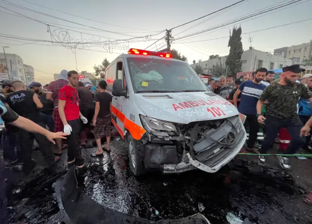 فلسطينيون يتفقدون الأضرار بعد إصابة قافلة سيارات إسعاف عند مدخل مستشفى الشفاء في مدينة غزة