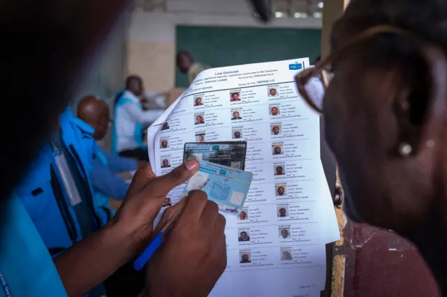 Un agent de la Commission nationale indépendante (CENI) vérifie une carte électorale dans un bureau de vote à l'école Saint-Georges, à Kinshasa, le 20 décembre 2023.