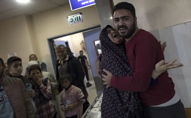 أم فلسطينية تعانق أحد أقاربها في مستشفى ناصر في خان يونس، جنوبي قطاع غزة،  بعد تلقيها نبأ وفاة ابنها في أعقاب الغارات الجوية الإسرائيلية.