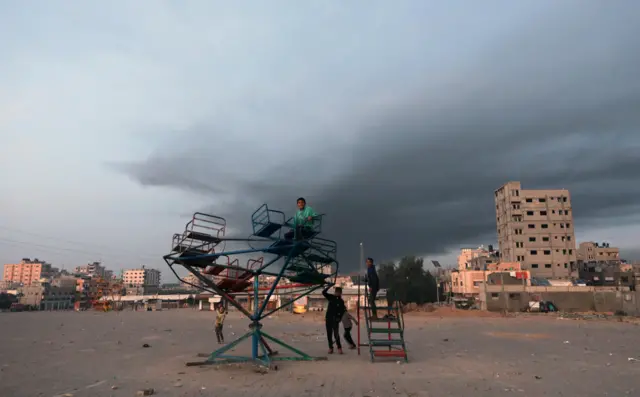 يلعب الأطفال مع تصاعد الدخان بعد ضربات جوية إسرائيلية في قطاع غزة