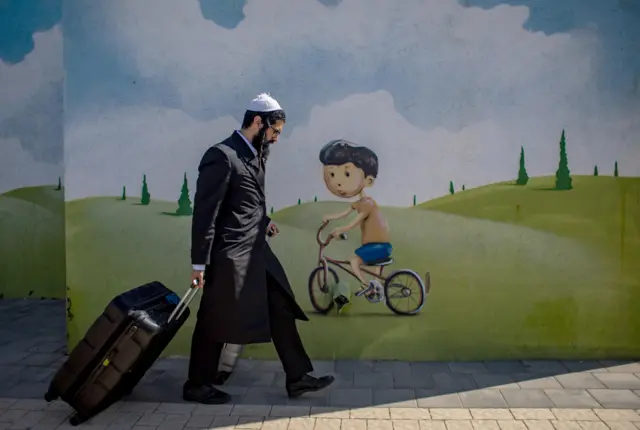 رجل إسرائيلي يصل إلى موقف الحافلات أثناء إجلاء السكان المحليين من سديروت