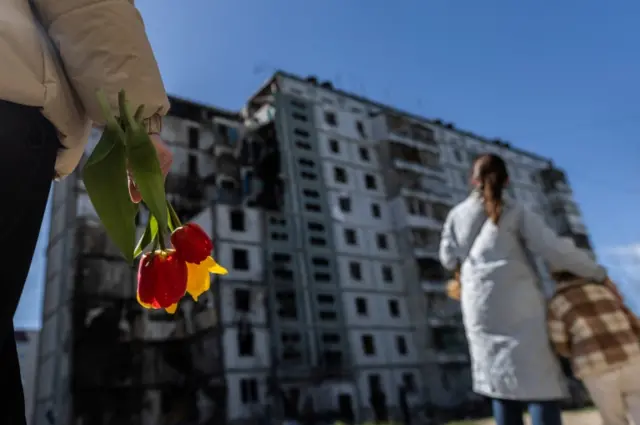 К дому приходят люди с цветами