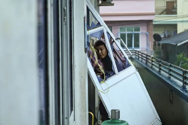 মিয়ানমারের রাখাইন রাজ্যে ঝড়ে ভেঙ্গে যাওয়া দরজার ভেতর দিয়ে তাকিয়ে রয়েছেন একজন বাসিন্দা