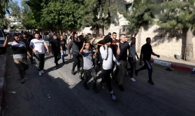 Falastiiniyiin sida meydka qof dhintay oo maraya mid ka mid ah waddooyinka xerada Jeniin