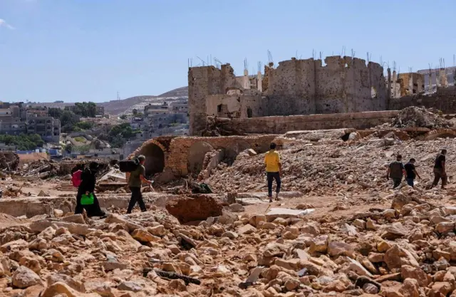 أشخاص يسيرون وسط الأنقاض، في أعقاب العاصفة التي ضربت درنة، ليبيا