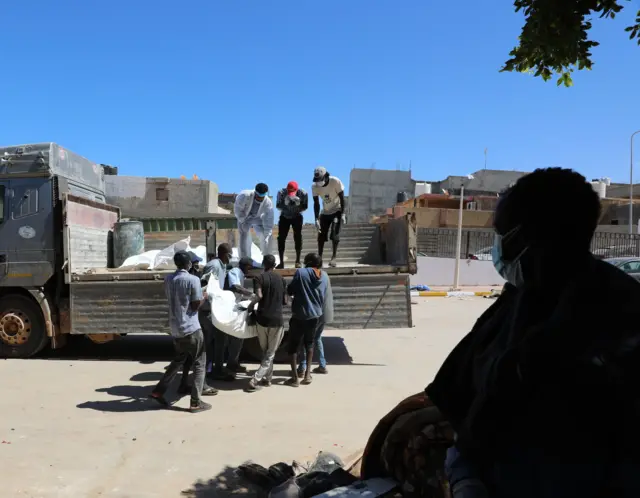 عمال الإنقاذ ينقلون أكياس الجثث التي تحتوي على بقايا ضحايا الفيضانات، التي جُرفت إلى الشاطئ