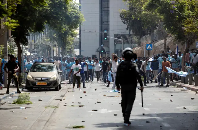 متظاهرون يحملون العصي والأعلام خلال مظاهرات عنيفة لطالبي اللجوء الإريتريين، بما في ذلك مؤيدو ومعارضو الحكومة الإريترية، في تل أبيب