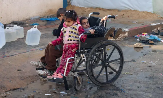 أطفال فلسطينيون يجلسون على كرسي متحرك