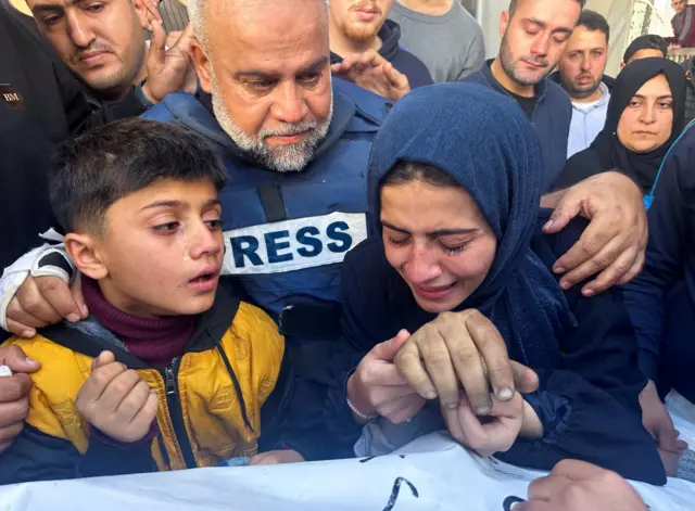 صحفي الجزيرة وائل الدحدوح يعانق ابنته وابنه أثناء حضورهما جنازة ابنه الصحفي الفلسطيني حمزة الدحدوح.