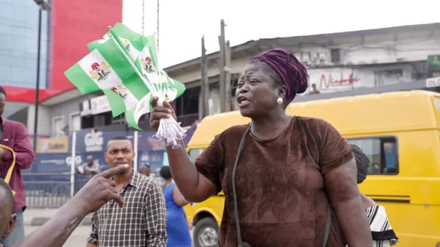 Nigerian woman dey sell flags on Nigeria 64th independence day