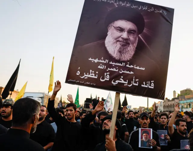 مؤيد لحزب الله يحمل ملصق للأمين العام للحزب حسن نصر الله الذي قُتل في غارة جوية إسرائيلية في بيروت، بغداد، العراق، 29 سبتمبر، 2024