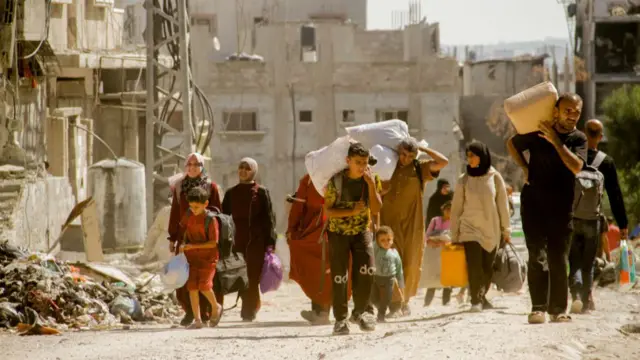 उत्तरी ग़ज़ा में घरों को छोड़कर जाते हुए लोग