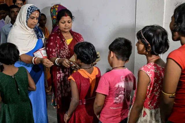 ओडिशा के बालासोर में बच्चों को राहत सामग्री देतीं महिलाएं
