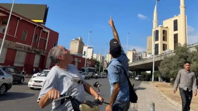 बेरूत के आसमान में मंडराते एक ड्रोन की ओर इशारा करता शख़्स