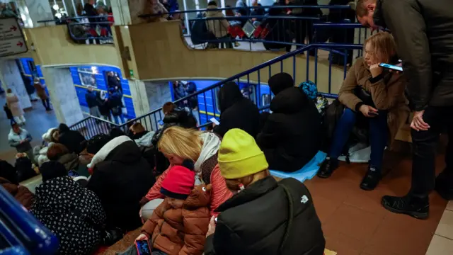 Люди сидят на лестнице на станции метро в Киеве