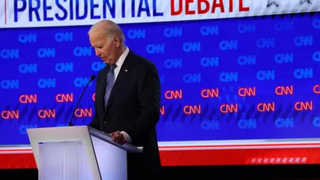 Biden olhando para baixo em palanque