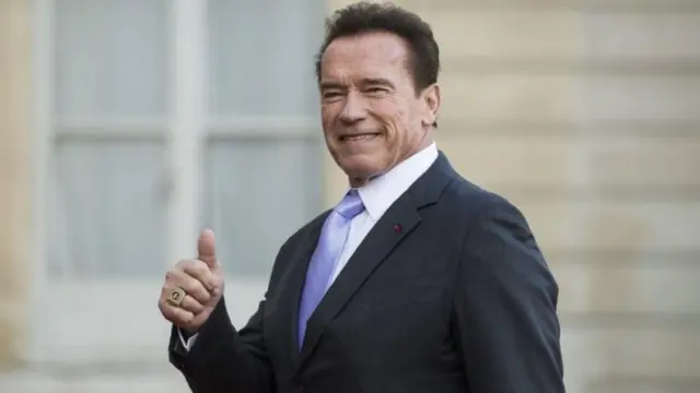 Arnold Schwarzenegger, um homem branco idoso forte de terno