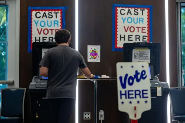 Homem de pé em frente e um local de votação