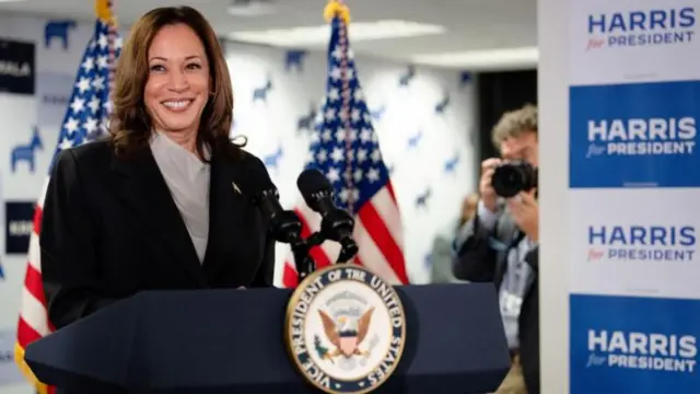 Kamala sorrindo em frente a palanque