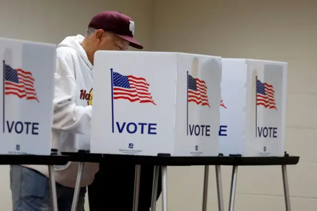 Homem votando em urna; há algumas urnas enfileirada