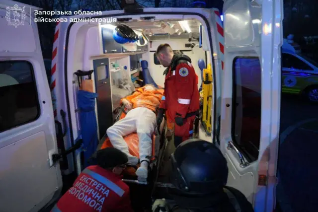 Пострадавшую женщину помещают в машину скорой помощи