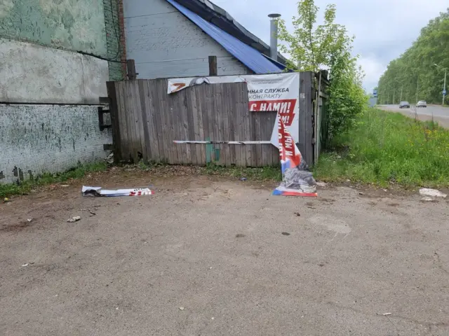 Наполовину сорванный с забора баннер