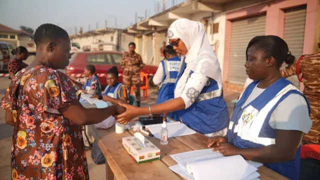 Electoral officers on blue accrediting a voter